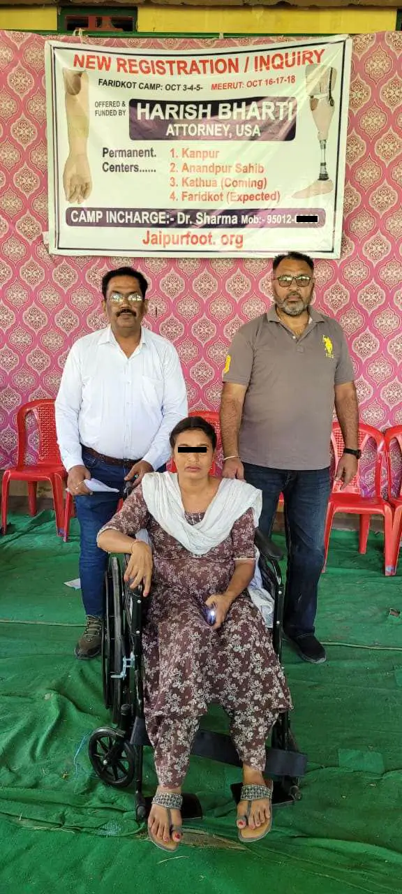 A woman in a wheelchair with two men standing behind her.