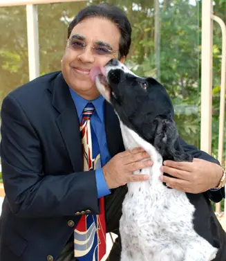 A man in a suit and tie holding a dog.